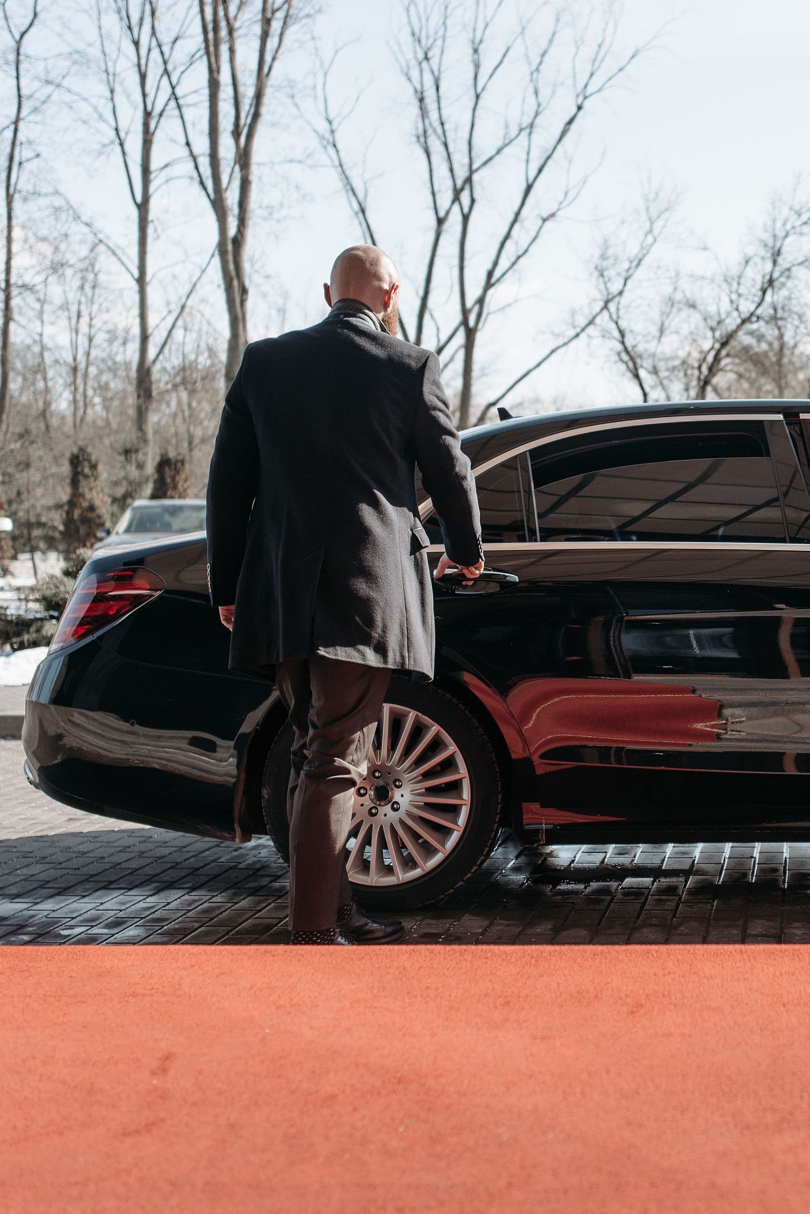Businessman approaching an executive car in bright daylight